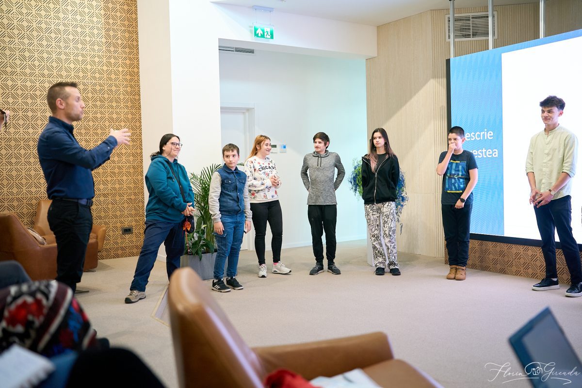 Curs de vorbit în public cu adolescenți și trainer într-o sală modernă, participanții sunt implicați într-un exercițiu.